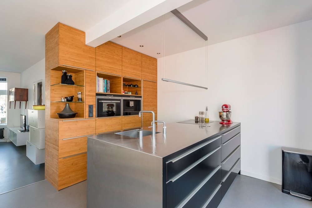 RVS eiland in combinatie met zwart zijdeglans fronten. Hoge kasten in bamboe caramel.